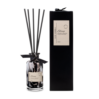 A black tortoiseshell Diffuser bottle with black reeds and packaging on a white background
