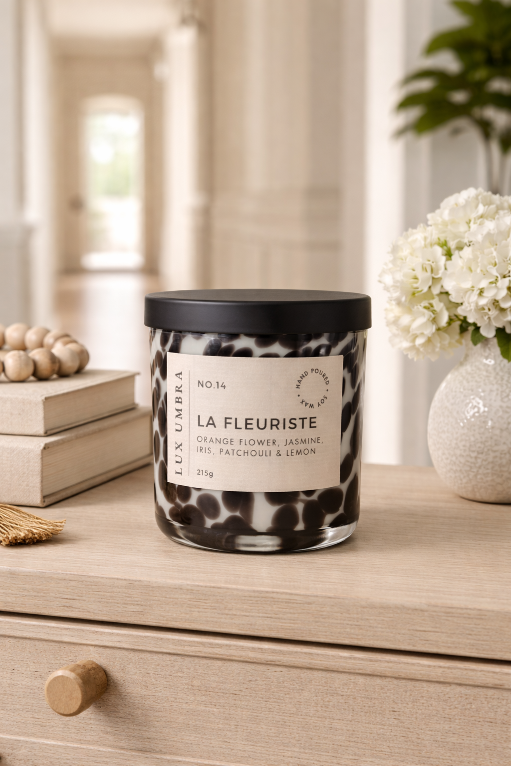 Candle labeled 'La Fleuriste' on a wooden surface with a blurred background