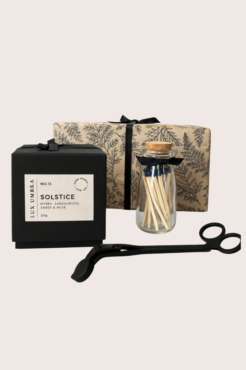 Set of matches, candle, wick trimmer and prettily wrapped box on a beige background.