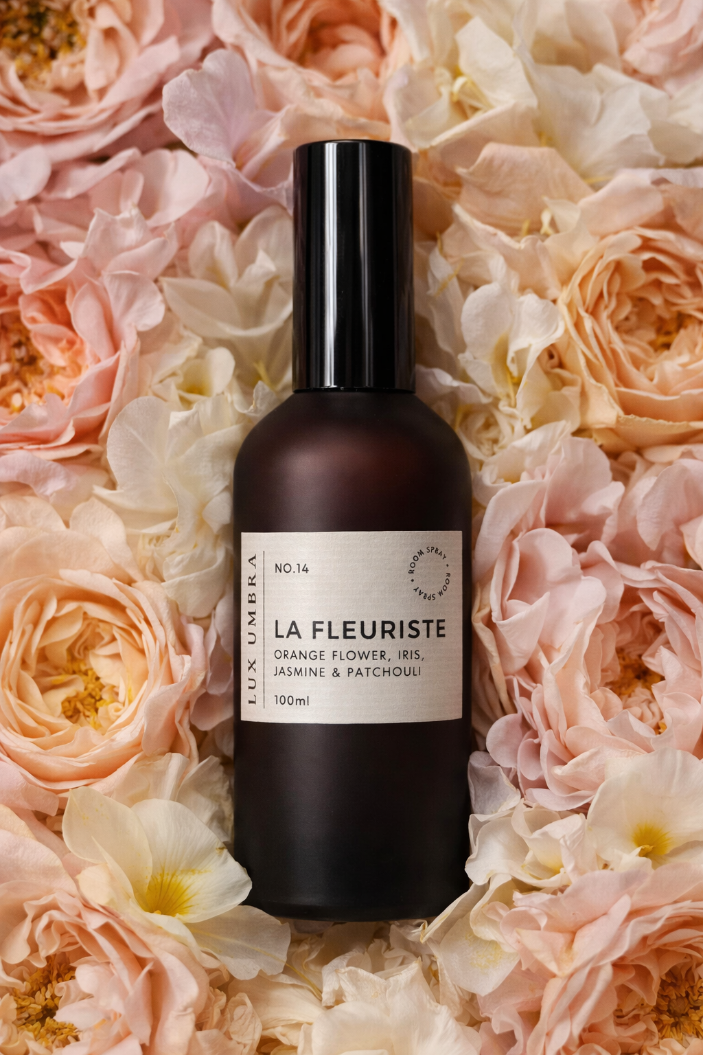 Bottle of La Fleuriste room spray surrounded by pink and white flowers