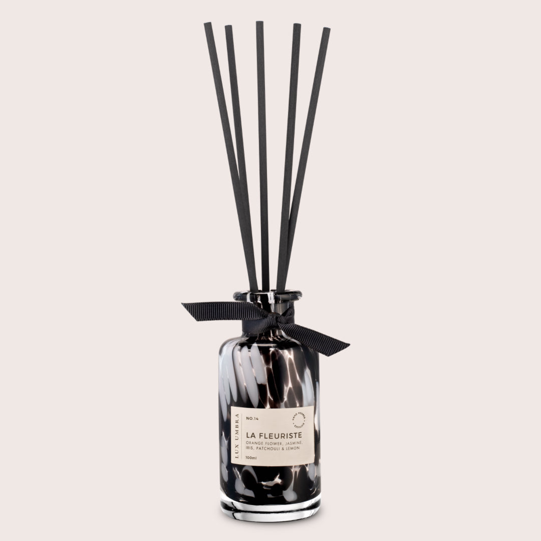 Black and white tortoiseshell patterned diffuser with black reeds, on a neutral background