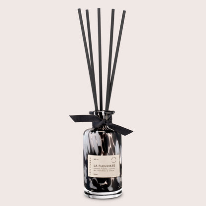 Black and white tortoiseshell patterned diffuser with black reeds, on a neutral background