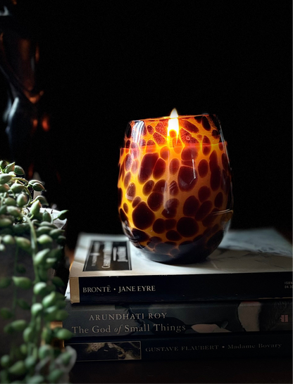A tortoiseshell candle in a stack of books with a plant 