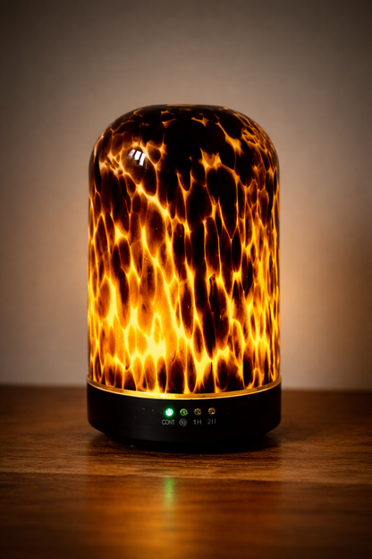 A lit up brown tortoiseshell diffuser on a wooden surface with a neutral background