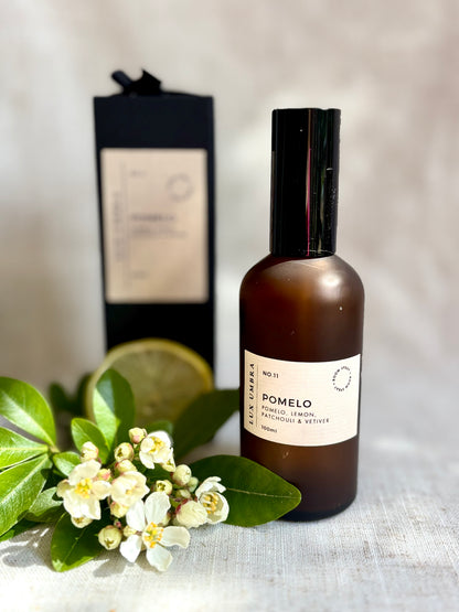 A room spray bottle and packaging for a room spray called pomelo, surrounded by blossom. 