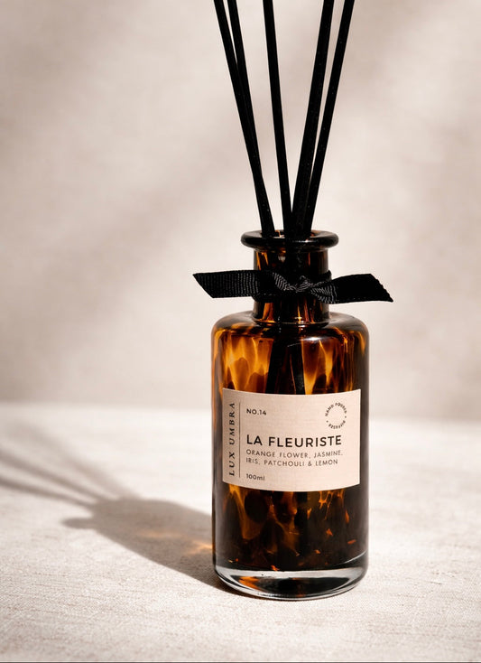 A tortoiseshell-patterned diffuser bottle with black reeds on a neutral background