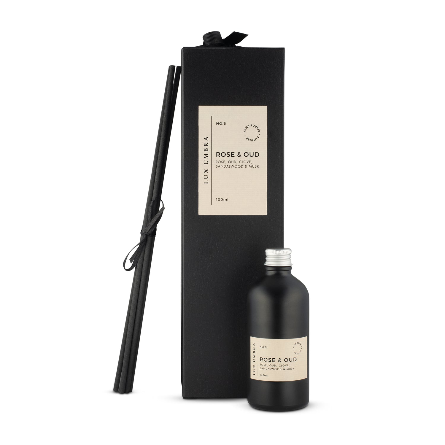 A black glass bottle with a diffuser refill labeled 'ROSE & OUD', accompanied by six black fibre reeds, presented in a luxurious black gift box tied with a black grosgrain ribbon.