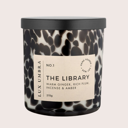 A black tortoiseshell candle called the library by Lux Umbra. On a beige background. 