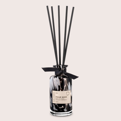 A black tortoiseshell reed diffuser with black reeds, with a fig scent. On a beige background