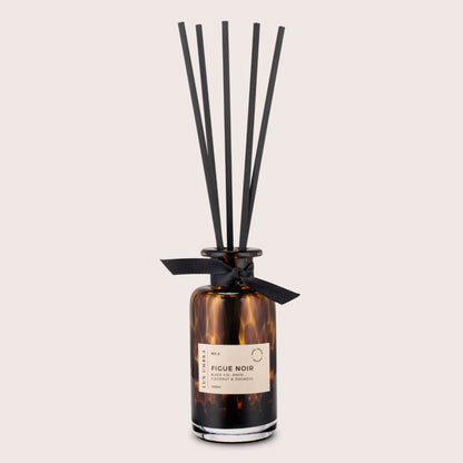 Brown tortoiseshell diffuser with black reeds, named Figue Noir. On a beige background